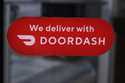 A DoorDash sign is posted on the door of a Dunkin' Donuts franchise, February 27, 2023, in Methuen,…