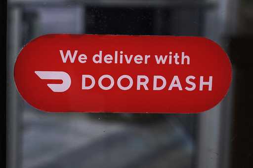 A DoorDash sign is posted on the door of a Dunkin' Donuts franchise, February 27, 2023, in Methuen,…