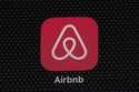 The Airbnb app icon is displayed on an iPad screen in Washington, D