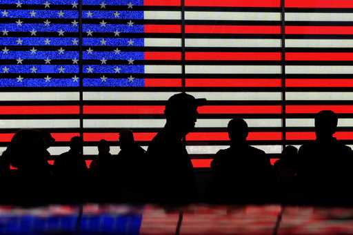 People gather near an electronic display of an American flag in Times Square in New York on August …