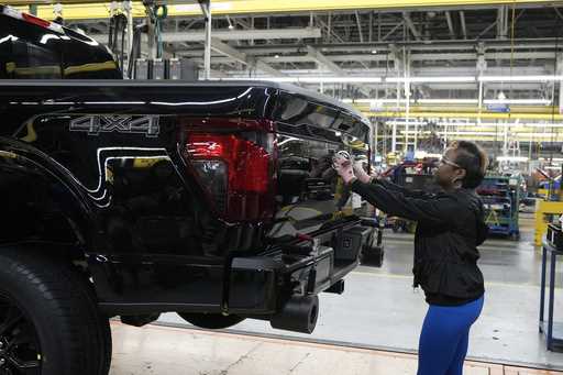 Assembly line worker Lashunta Harris applies the Ford logo on a 2024 Ford F-150 truck being assembl…
