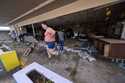 Kegan Ward, assistant manager of Swami Spirits, walks through debris of the damaged store in the af…