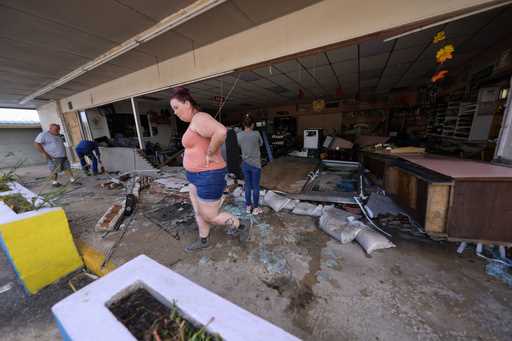 Kegan Ward, assistant manager of Swami Spirits, walks through debris of the damaged store in the af…