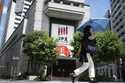 A person walks in front of an electronic stock board showing Japan's Nikkei index at a securities f…