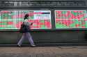 FILE -A passerby moves past an electronic stock board showing Japan's Nikkei 225 index and stock pr…