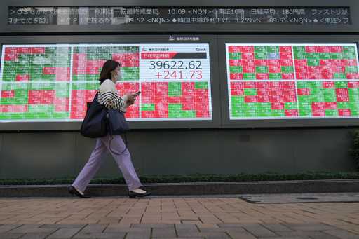 FILE -A passerby moves past an electronic stock board showing Japan's Nikkei 225 index and stock pr…