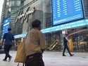 People walk past Hong Kong's stock exchange building as the market closed with a massive fall of mo…