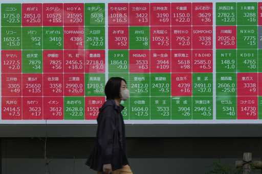 A passerby moves past an electronic stock board showing Japan's stock prices outside a securities f…