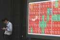 A person stands near an electronic stock board showing Japan's Nikkei index at a securities firm in…