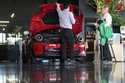 A salesperson shows an unsold 2024 Cooper SE electric hardtop to a prospective buyer in the showroo…