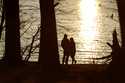 A couple stands at the banks of the Loch Raven Reservoir as the sun begins to set, February 19, 202…