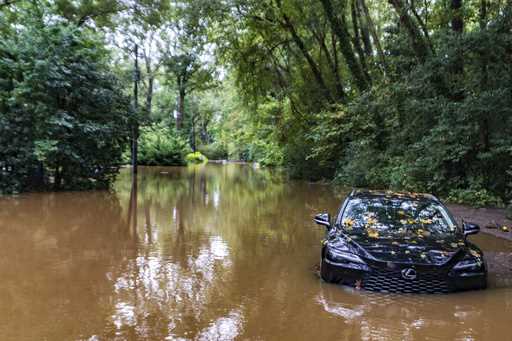 A partially submerged vehicle sits in flood water from after Hurricane Helene passed the area, Frid…