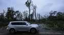 Vehicles move slowly around trees that have fallen after Hurricane Helene moved through the area, S…