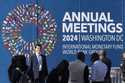 An attendee poses for a photograph in front of a sign advertising the annual meetings of the Intern…