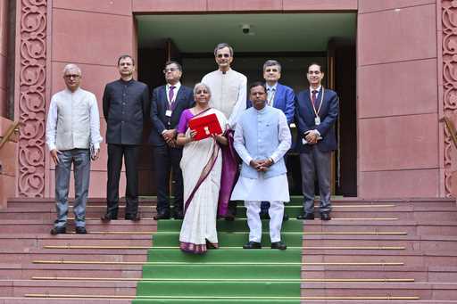 Indian Finance Minister Nirmala Sitharaman, carrying a red pouch containing budget documents, poses…