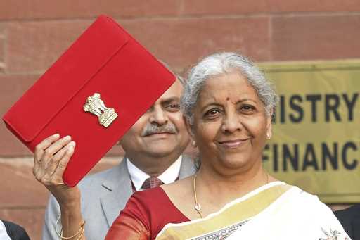 Indian Finance Minister Nirmala Sitharaman shows a red pouch containing budget documents, as she ar…