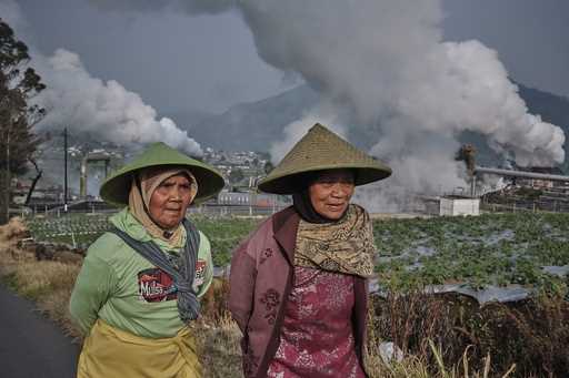 Farmers walk by as steam rises from a geothermal power plant in Dieng, Central Java, Indonesia, Nov…