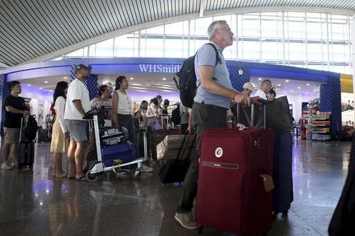 Passengers look at a flight information board after a number of flights are cancelled due to the er…