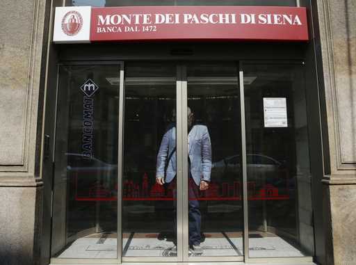 A man waits for the sliding doors to open to exit a Monte dei Paschi di Siena bank branch, in Milan…