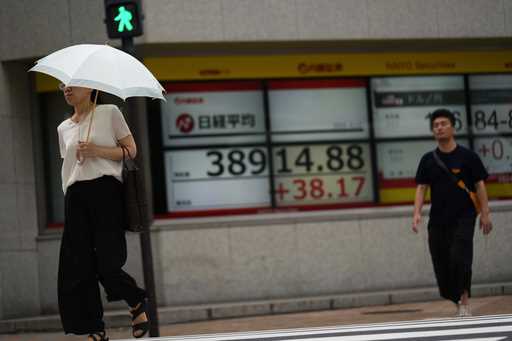 People walk in front of an electronic stock board showing Japan's Nikkei 225 index at a securities …