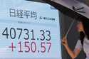 A passerby walks past an electronic stock board showing Japan's Nikkei 225 index at a securities fi…