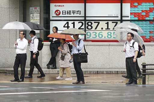 A person walks in front of an electronic stock board showing Japan's Nikkei index at a securities f…