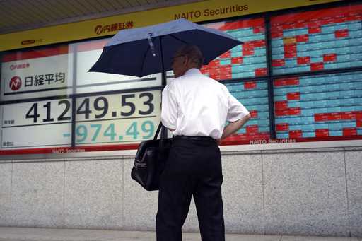 A person stops to look at an electronic stock board showing Japan's Nikkei index at a securities fi…