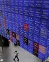 A person walks below an electronic stock board in Tokyo Thursday, July 25, 2024