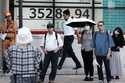 People stand near an electronic stock board showing Japan's Nikkei index at a securities firm Monda…