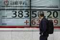 A person looks at an electronic stock board showing Japan's Nikkei index at a securities firm Tuesd…