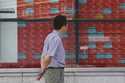 A person looks at an electronic stock board showing Japan's stock prices, at a securities firm Thur…