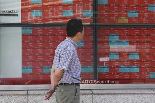 A person looks at an electronic stock board showing Japan's stock prices, at a securities firm Thur…