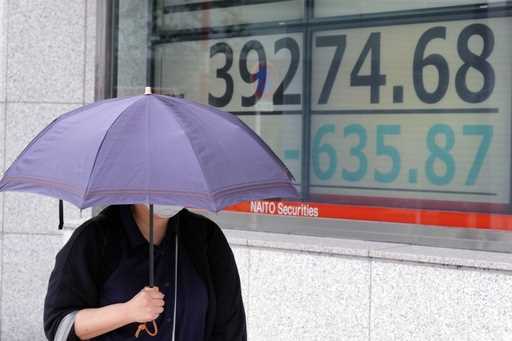 A person walks in front of an electronic stock board showing Japan's Nikkei index at a securities f…