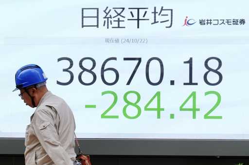 A person walks in front of an electronic stock board showing Japan's Nikkei index at a securities f…