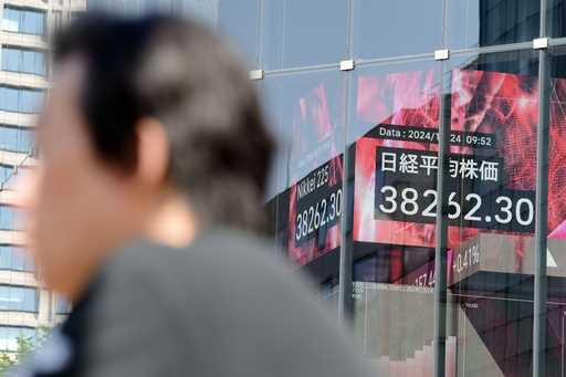 A person stands near an electronic stock board showing Japan's Nikkei index at a securities firm Th…