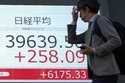 A person walks in front of an electronic stock board showing Japan's Nikkei index at a securities f…