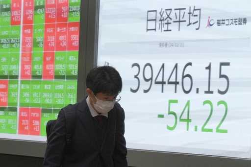 A person walks in front of an electronic stock board showing Japan's Nikkei index at a securities f…