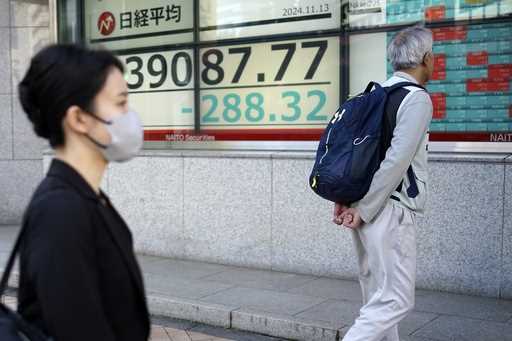 Person walk in front of an electronic stock board showing Japan's Nikkei index at a securities firm…