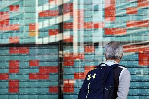 A person looks at an electronic stock board showing Japan's Nikkei index at a securities firm Wedne…