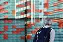 A person looks at an electronic stock board showing Japan's Nikkei index at a securities firm Wedne…