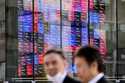 People walk past an electronic stock board showing Japan's stock prices Thursday, November 28, 2024…