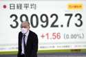 A person walks in front of an electronic stock board showing Japan's Nikkei index at a securities f…