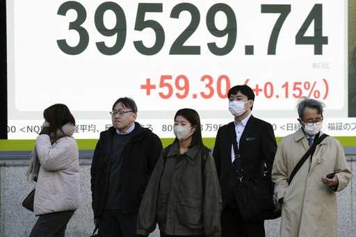 People stand in front of an electronic stock board showing Japan's Nikkei index at a securities fir…