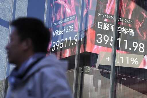 A person stands in front of an electronic stock board showing Japan's Nikkei index at a securities …