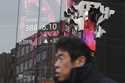 A person walks in front of an electronic stock board showing Japan's Nikkei index at a securities f…