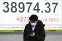 A person walks in front of an electronic stock board showing Japan's Nikkei index at a securities f…