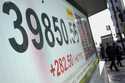 People walk in front of an electronic stock board showing Japan's Nikkei index at a securities firm…