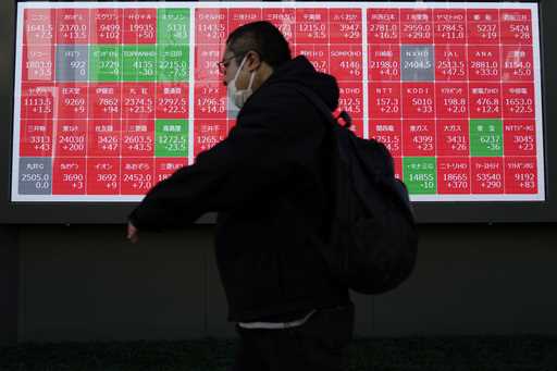 A person walks in front of an electronic stock board showing Japan's Nikkei index at a securities f…