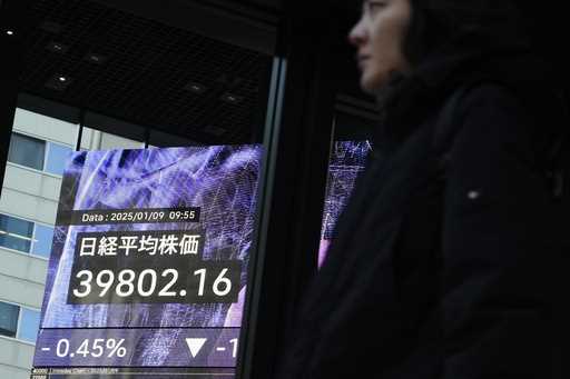 People stand in front of an electronic stock board showing Japan's Nikkei index at a securities fir…