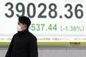 A person walks in front of an electronic stock board showing Japan's Nikkei index at a securities f…